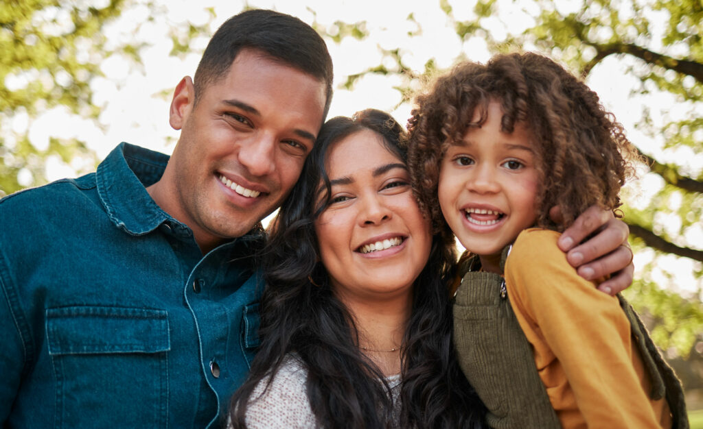 Close-up of a happy child, mother and father in an outdoor setting.