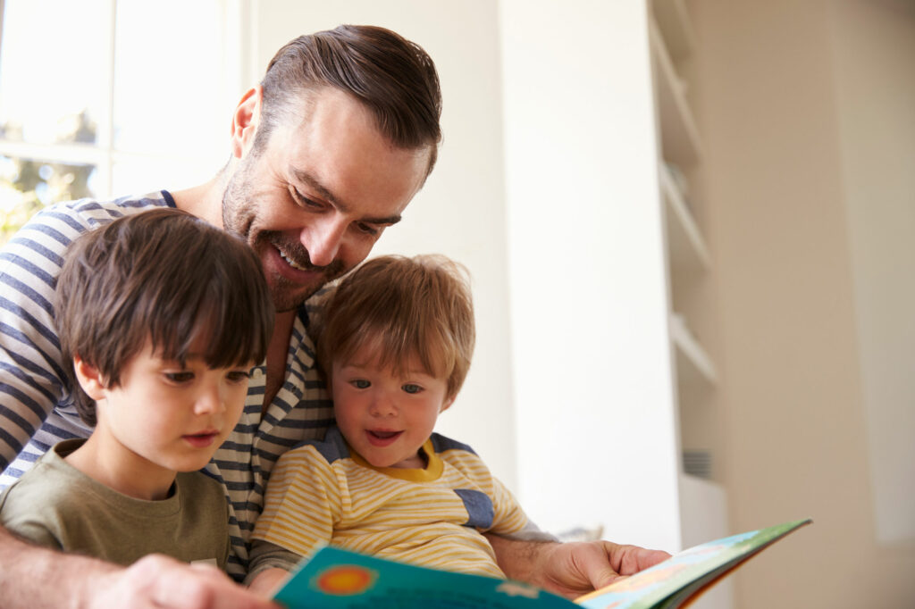 Close up of a father reading a storybook to his two sons.